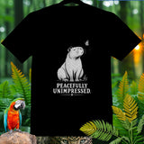 Black t-shirt with a capybara and butterfly graphic, text reads PEACEFULLY UNIMPRESSED.