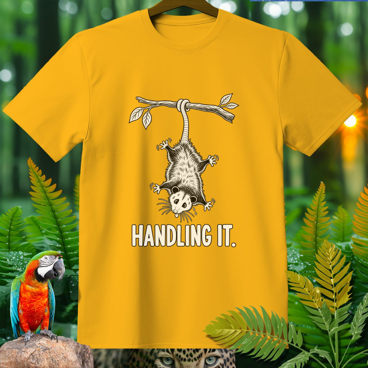 Yellow t-shirt with a possum hanging from a branch and the text "HANDLING IT."