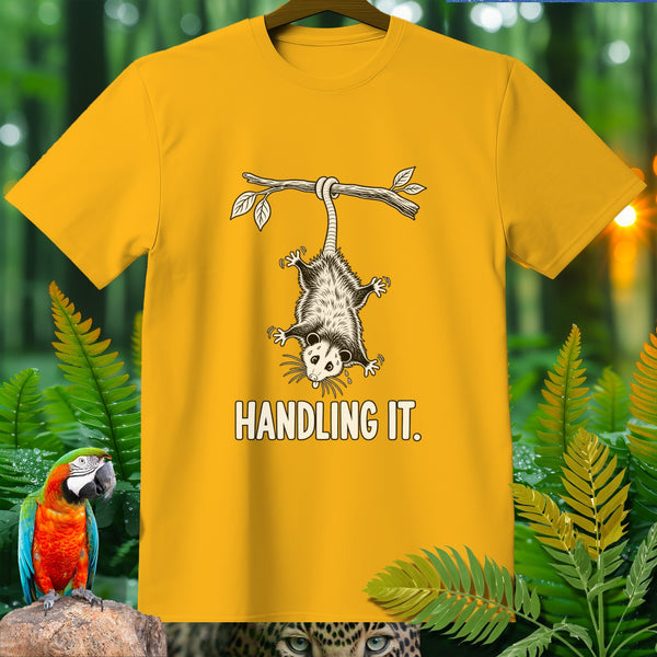 Yellow t-shirt with a possum hanging from a branch and the text "HANDLING IT."