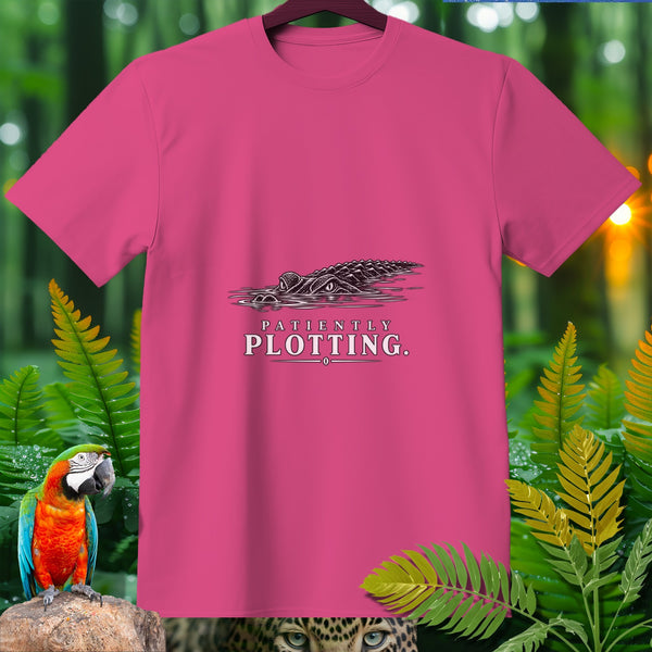 Pink t-shirt with alligator and text "PATIENTLY PLOTTING." design.