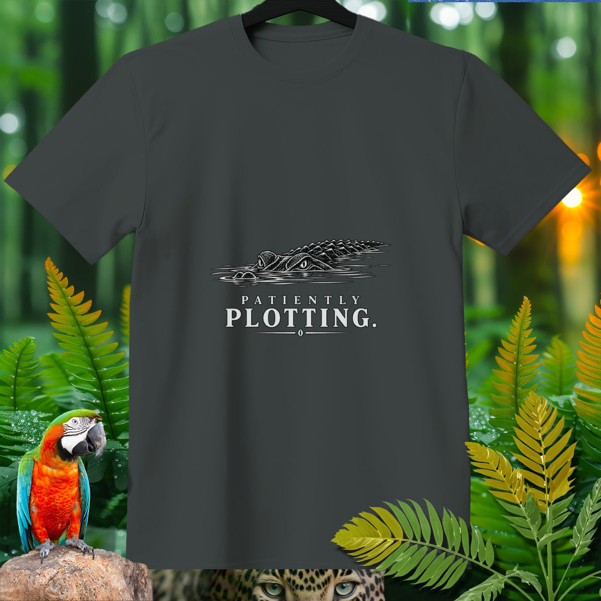 Dark grey t-shirt with an alligator illustration and "PATIENTLY PLOTTING." text.