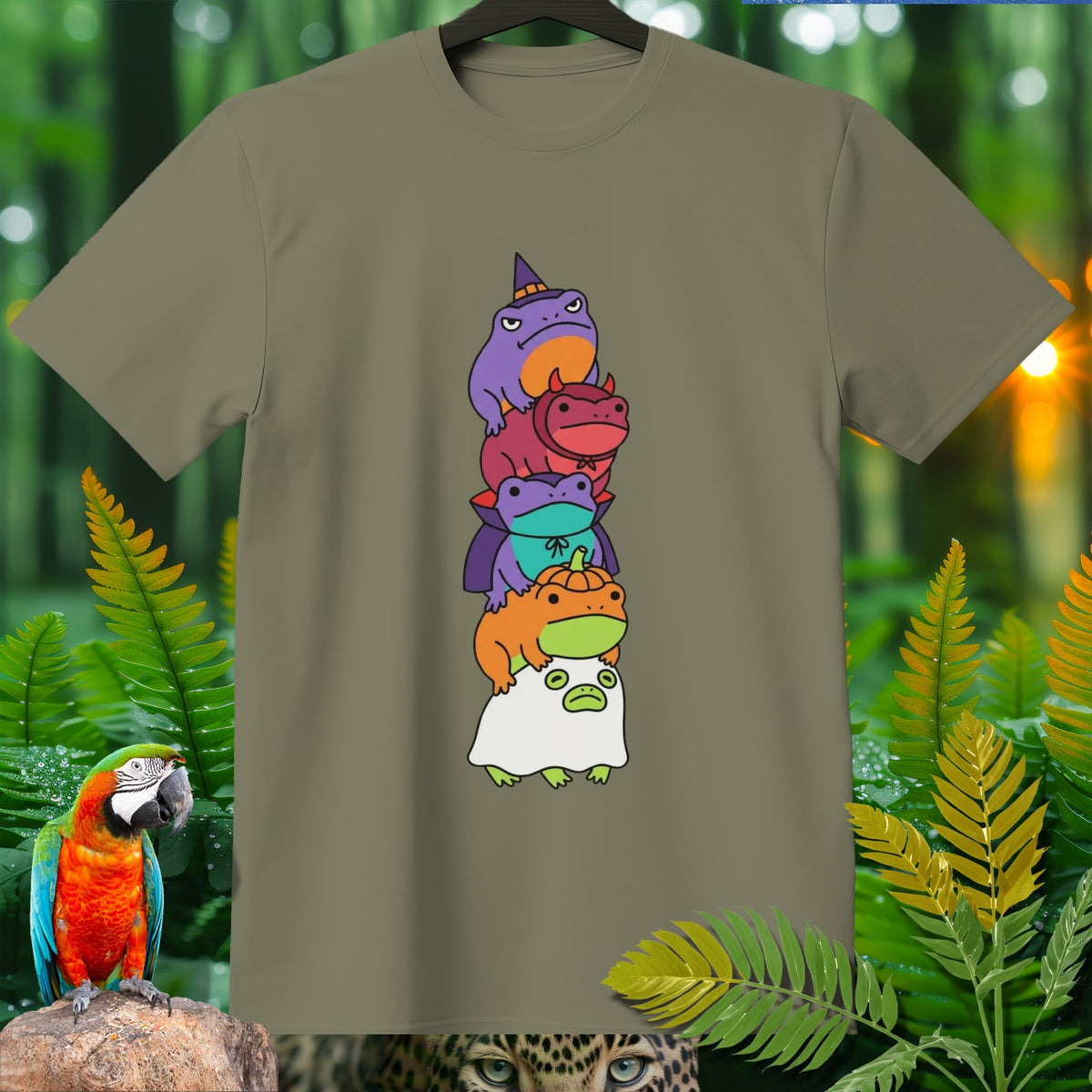 Stack of five cartoon frogs dressed in Halloween costumes on a tan t-shirt.