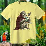 Gorilla in vampire cape drinking coffee with bat on a light yellow t-shirt.