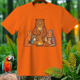 Bear, fox, raccoon, rabbit, wolf, and owl gathered around a campfire with pumpkins.