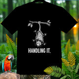 Black t-shirt with a graphic of an opossum hanging from a branch, text 
