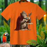 Gorilla in vampire cloak drinking tea with a bat, on an orange t-shirt.