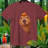 Maroon t-shirt featuring a capybara with an orange on its head.