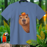 Capybara with an orange on its head on a blue t-shirt with jungle background.