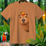 Capybara with an orange on its head on a brown t-shirt with jungle foliage.