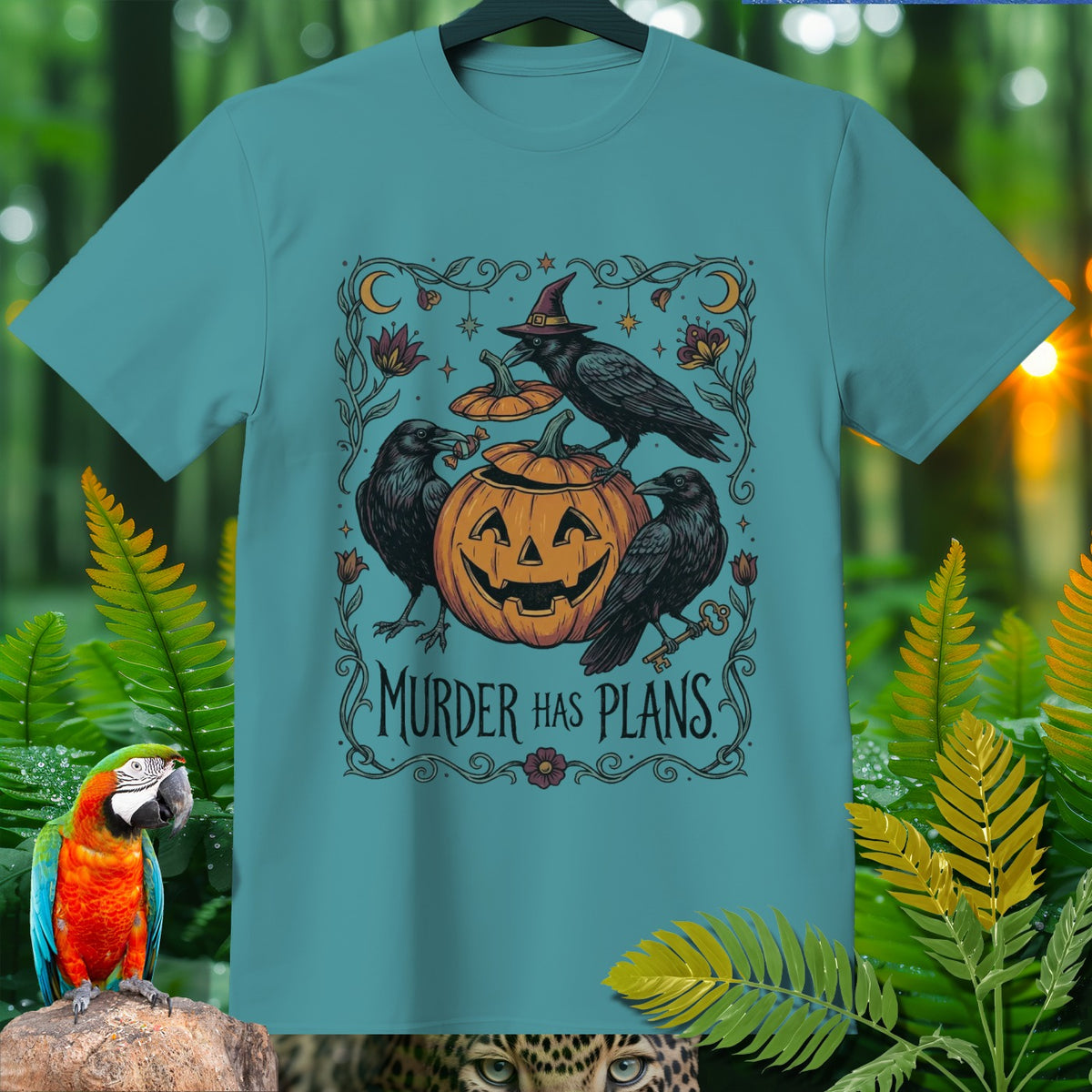 Teal t-shirt with Halloween graphic featuring crows, pumpkin, and text "Murder Has Plans".