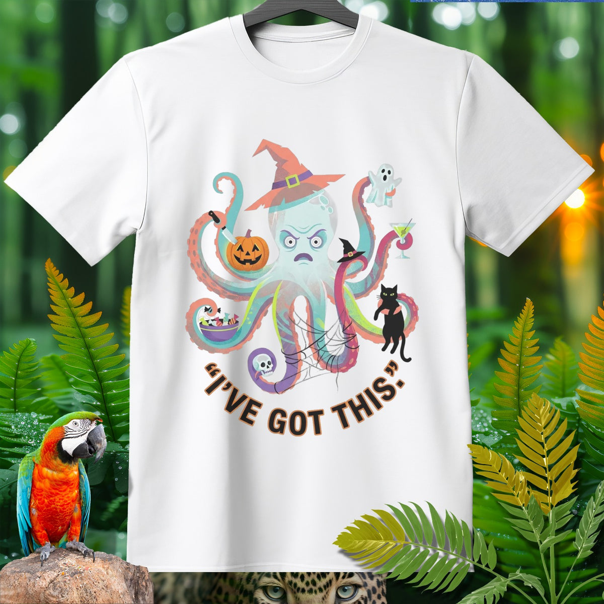 White t-shirt with a cartoon octopus wearing a witch hat and holding Halloween items.