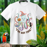White t-shirt with a cartoon octopus wearing a witch hat and holding Halloween items.
