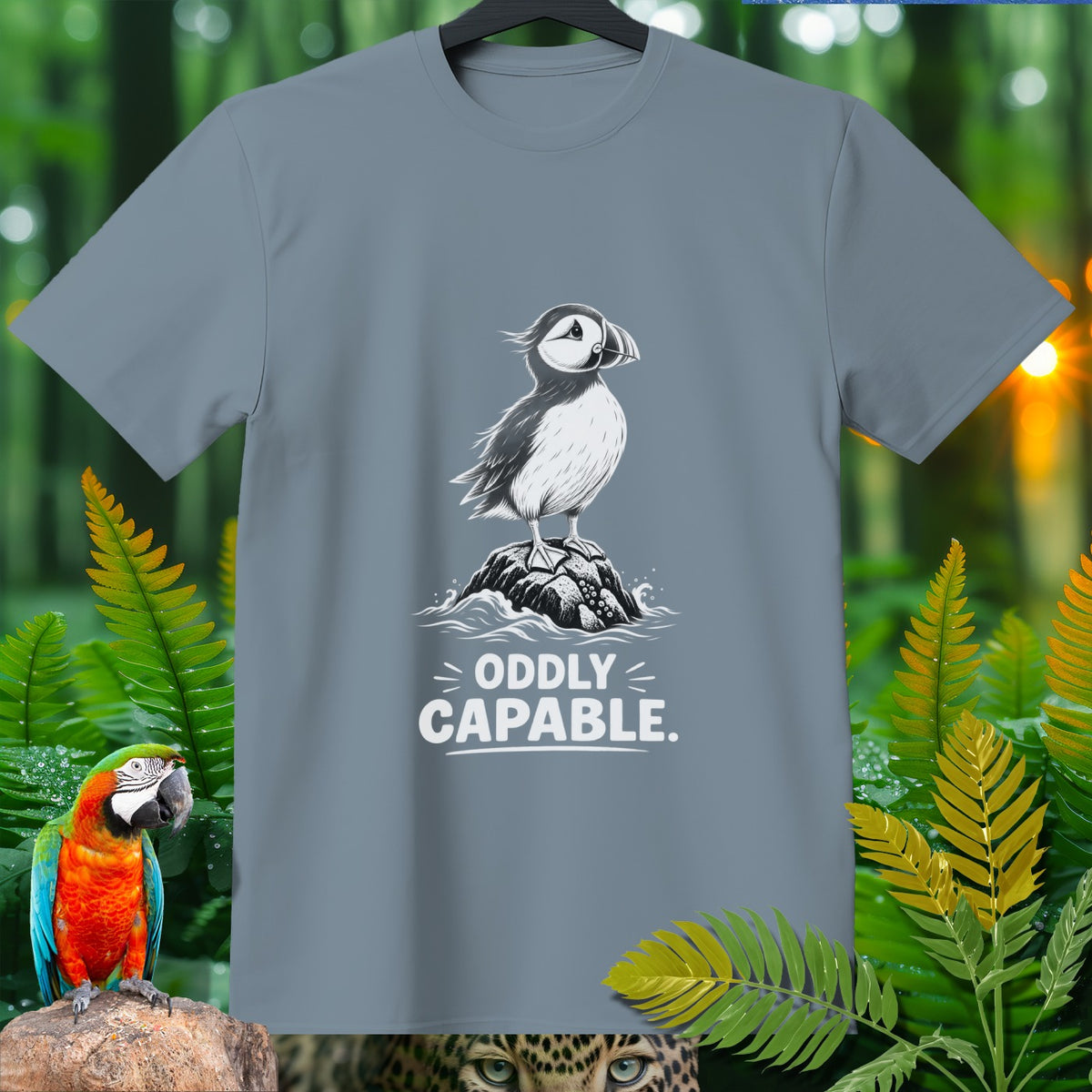Grey t-shirt with graphic of a puffin on a rock and text "ODDLY CAPABLE."