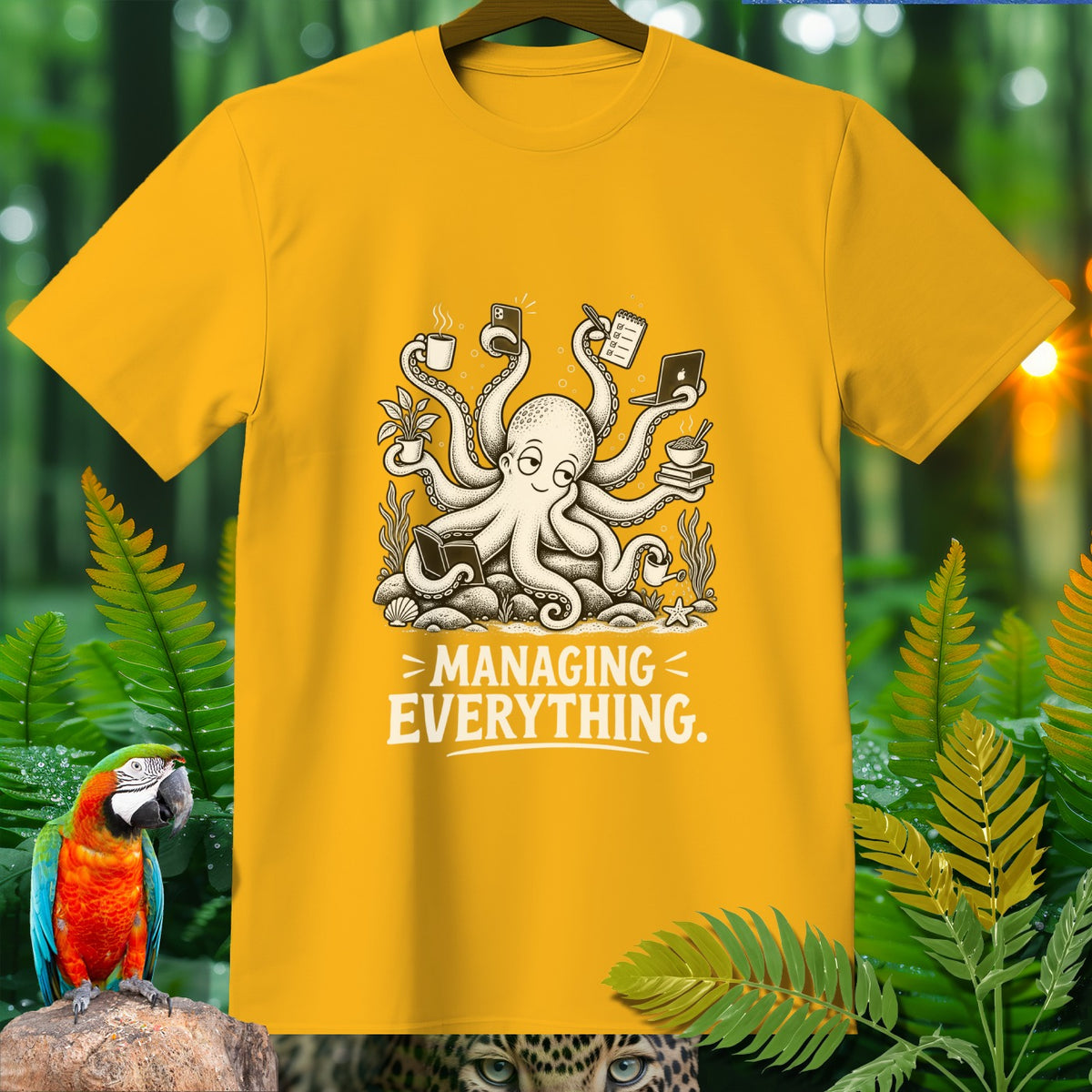 Yellow t-shirt with a cartoon octopus juggling coffee, phone, laptop, and books, text "MANAGING EVERYTHING."