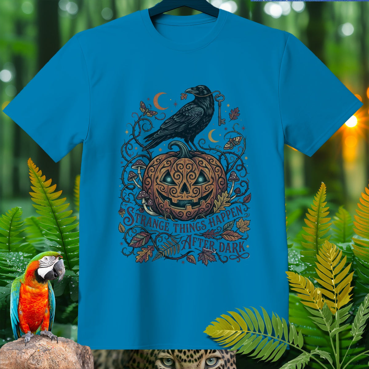 Blue t-shirt with Halloween design: crow, pumpkin, moon, and text "Strange Things Happen After Dark".