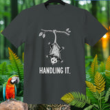 T-shirt with a graphic of an opossum hanging from a branch that says 